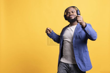 Photo for Happy african american person having fun, dancing on rhythm, enjoying leisure time. Cheerful BIPOC man entertaining himself doing funky movements on music, studio background, camera A - Royalty Free Image