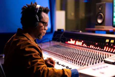 Foto de Audio afroamericano experto editando pistas en estudio de grabación profesional, mezclando y masterizando música en sala de control con equipo técnico. Ingeniero de sonido produciendo nuevas pistas para un álbum. - Imagen libre de derechos