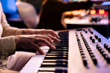 Photo for Male artist playing notes on electronic midi controller in studio, composing a new song with piano keyboard synthesizer. Skilled musician making a live performance in control room, music production. - Royalty Free Image