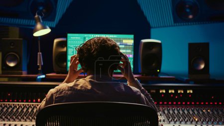 Photo for Mixer producer develops audio by editing recordings and integrating additional sounds using buttons on mixing console. Engineer in sound design uses motorized faders at production studio. Camera B. - Royalty Free Image