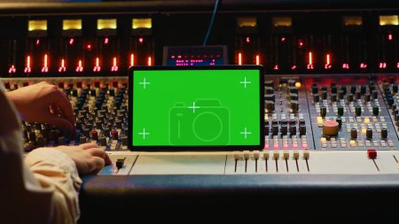 Audioexperten mischen und Mastering-Melodien auf Schnittsoftware neben dem Greenscreen-Tablet und produzieren und aufnehmen Tracks durch Drücken von Tasten und Fadern. Tontechniker in der Regie. Kamera A.