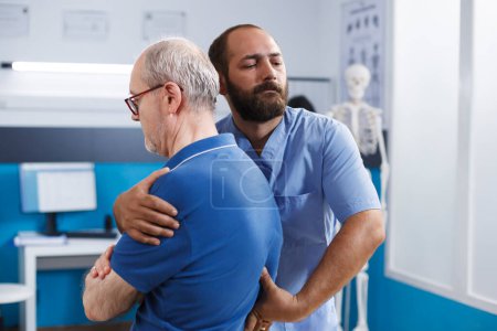 Elderly guy receiving rehabilitation from chiropractor for back pain and spinal injuries. Nurse practitioner helping retired patient heal from accident and providing chiropractic care for treatment.