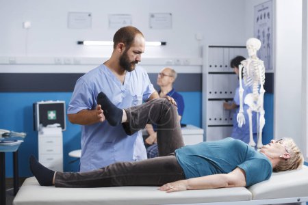Physiotherapist stretching leg muscle to relieve pressure for recovery of senior woman. Doctor assistant helping aged patient with knee pain, doing physical exercise for physical therapy.