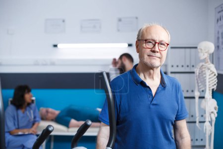 Porträt eines pensionierten Patienten, der ein physikalisches Therapiezentrum besucht. Älterer Mann blickt in die Kamera und bereitet sich in einer Reha-Klinik auf seine Genesung durch Bewegung und Fitness vor.