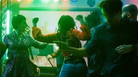 Photo for Persons having fun at dance party in nightclub, enjoying modern dance battle to show off funky moves on dance floor. Happy young adults dancing and jumping around on music mix. - Royalty Free Image