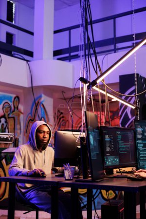Un criminel afro-américain piratant le serveur et piratant le mot de passe sur ordinateur. Pirate enfreignant le système de cybersécurité et faisant des activités criminelles illégales tard dans l'entrepôt abandonné