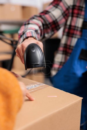 Photo for Warehouse employee scanning cardboard box barcode while doing inventory control. Delivery service operator managing parcel receiving and checking qr code with scanner close up - Royalty Free Image