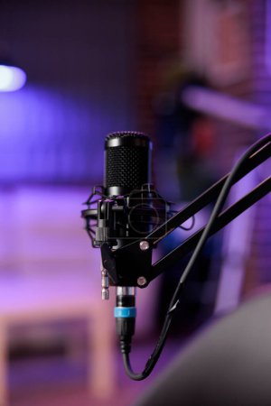Close up shot of podcast microphone used to record conversations for internet livestreaming show. Streaming sound capturing and recording technology in empty home studio with neon lights