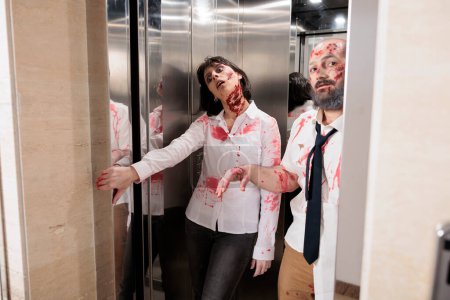 Workers coming out of office building elevator dressed as creepy zombies during Halloween holiday. Colleagues covered in fake scars pretending to be feral cadavers exiting escalator