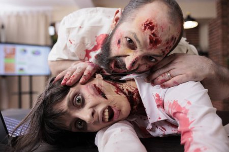 Kollegen amüsieren sich im Büro als Zombies verkleidet zu Halloween und machen Selfies. Mann und Frau mit falschen blauen Flecken, die sich als Untote ausgeben, fotografieren mit Selfie-Kamera