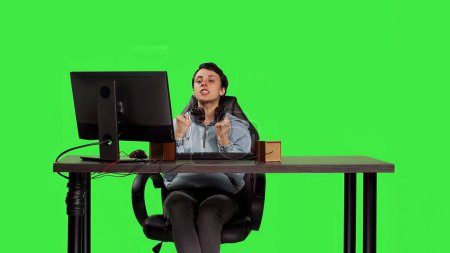 Jeune adulte jouant à des jeux vidéo sur ordinateur au bureau sur fond d'écran vert, gagner tournoi mondial sur PC. Femme joueuse se sentant heureuse et heureuse de son succès. Caméra B.