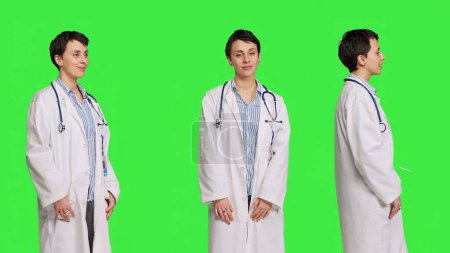 Photo for Portrait of physician wearing a white coat and a stethoscope for exams, standing against greenscreen backdrop. Doctor specialist working in healthcare industry, medical expertise. Camera B. - Royalty Free Image