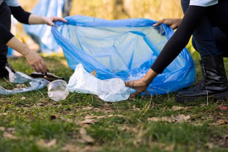 Ehrenamtliche Frauen säubern den Wald, indem sie Müll in Tüten einsammeln und Kunststoffabfälle für einen nachhaltigen Lebensstil recyceln. Menschen sammeln Müll, engagieren sich ehrenamtlich gegen Umweltverschmutzung.