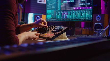 Erfahrener Toningenieur verwendet Mischpult, um neue Songs im Heimstudio aufzunehmen. Postproduktionsgeräte und Werkzeuge auf dem Computer, betreibt digitale Audio-Workstation-Software. Kamera B.