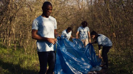 Diverse Freiwillige sammeln Müll und Unrat aus dem Waldgebiet ein, kämpfen gegen Umweltverschmutzung und Naturschutz. Eine Gruppe von Aktivisten säubert den Wald und recycelt Plastikmüll. Kamera B.