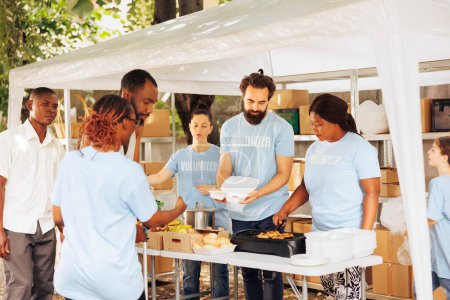 Un service empathique à l'équipe multiculturelle pauvre et nécessiteuse fait un don et fournit une aide humanitaire. Un homme afro-américain avec des béquilles reçoit l'aide d'une bénévole noire lors d'une collecte de nourriture.