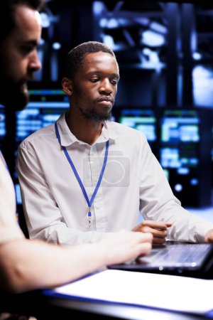 African american admin and coworker dealing with server farm system failures. Colleagues brainstorming ideas on how to best minimize supercomputers downtime and prevent crashes