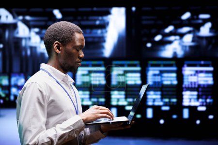 Afrikanischer Systemadministrator tippt Notfallplan für Supercomputer-Hub auf Laptop, um schnelle Wiederherstellung des Dienstes zu gewährleisten, Schaden zu begrenzen und Unterbrechungen des normalen Betriebs zu minimieren