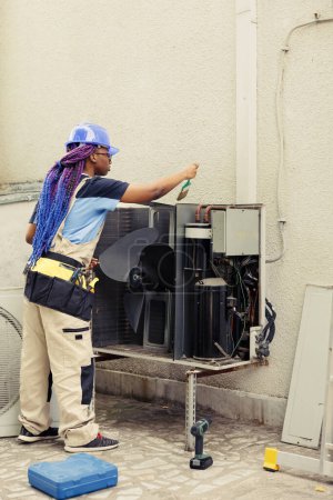 Professioneller Ingenieur mit der jährlichen Reinigung und Wartung des HVAC-Systems beauftragt, wobei er eine weiche Staubbürste verwendet, um die angehäufte Schmutz- und Schmutzschicht aus der Kondensatorspule zu entfernen