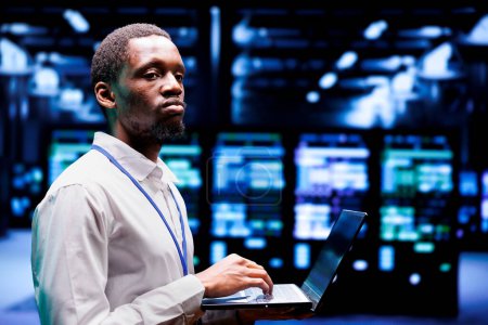 Afrikanische amerikanische Techniker schreiben High-Tech-Server Farm Katastrophenrettungsplan auf Laptop, um schnelle Wiederherstellung des Dienstes bieten, begrenzen Störungen und minimieren Unterbrechungen des normalen Betriebs