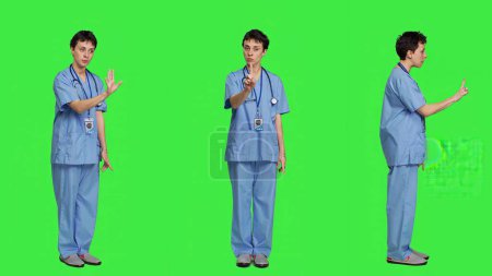Photo for Displeased irritated nurse shouting no and arguing with someone against greenscreen backdrop, showing rage and anger while she wears hospital scrubs. Aggressive medical assistant. Camera A. - Royalty Free Image