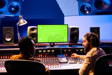 Photo for Musicians team working together on mixing tracks with isolated monitor screen, professional recording studio. Artist and audio technician using console and control panel board, knobs and faders. - Royalty Free Image
