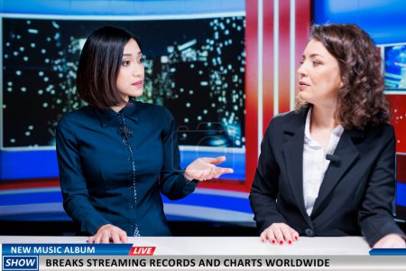 Photo for Journalists team talk about new music album, women night show hosts reveal song breaking top charts and records at global scale. Newscasters discuss about streaming and selling success. - Royalty Free Image