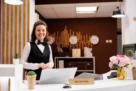 Front desk staff smiling at reception, welcoming hotel guests and providing luxury room services. Receptionist in formalwear being friendly, works on online bookings and reservations.