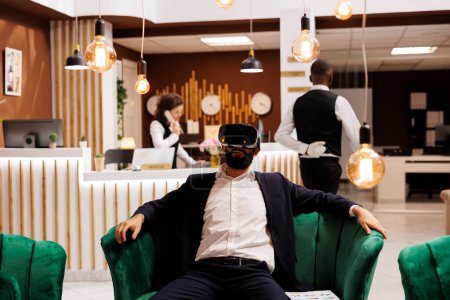 Geschäftsmann arbeitet mit vr-Headset in Hotellobby, mit neuen interaktiven 3D-Brillen vor dem Check-in-Prozess. Junge Erwachsene mit Virtual-Reality-Technologie auf Geschäftsreise.
