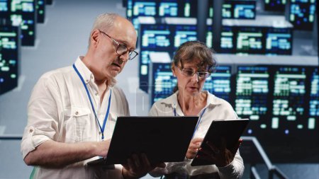 Fachkundige IT-Praktiker schauen sich auf der Serverfarm um, nutzen Laptop und Tablet, um Notfallpläne zu überprüfen und ersatzbedürftige Erpresser zu ermitteln, um Gefahren vorzubeugen