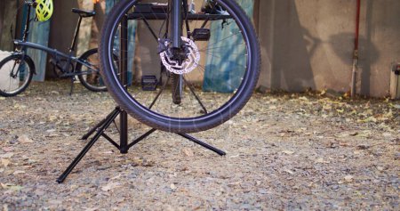 Photo for Detailed view of damaged bike mounted on repair-stand ready for repair with assortment of tools outdoor. Annual summer upkeeping and servicing of modern bicycle in home yard. - Royalty Free Image