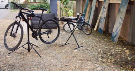Photo for View of modern damaged bikes placed and secured in home yard ready for maintenance with professional equipment. Aerial shot of bicycle on repair-stand next to specialized toolbox outdoor. - Royalty Free Image