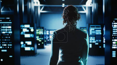 Employee walking through data center infrastructure clusters providing processing resources for different workloads. Engineer inspecting server rigs tasked with solving complex operations