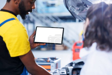 Mechanic in car service uses mockup tablet to order new radiator for faulty vehicle. Certified garage expert shows woman needed parts replacement on isolated screen device, close up
