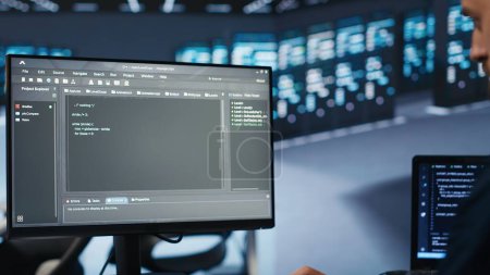 Systemadministrator läuft Skript auf Computerbildschirm in High-Tech-Rechenzentrum, um optimale Leistung zu gewährleisten. Arbeiter überwachen den Energieverbrauch, machen Checks auf Serverrackmounts Clustern