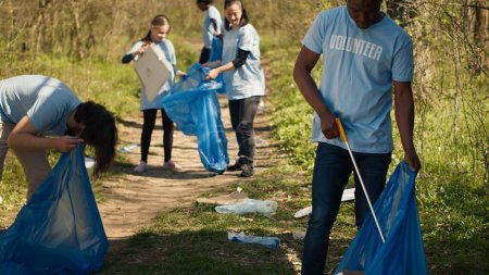 Umweltfreundlicher Aktivist greift sich Müll und Plastikmüll aus einem Waldgebiet, säubert den Wald und sammelt Müll in einem Müllsack ein. Ehrenamtlich kümmert sich der Mann um die Abfallwirtschaft. Kamera A.