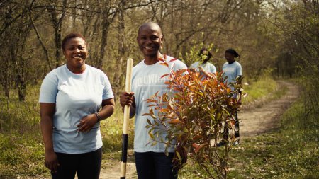 Portrait of african american couple fighting to preserve natural environment by planting trees, collecting rubbish and cultivating consciousness. Volunteers save the planet. Camera B.