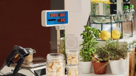Photo for Close up of electronic scale in eco friendly zero waste supermarket next to organic produce. Panning shot of weighing machine in local neighborhood shop used for bulk products - Royalty Free Image