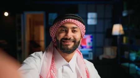 Point of view shot of arab content creator using smartphone to do live broadcast for subscribers, showing his home studio. Middle Eastern online star films himself using cellphone camera, POV