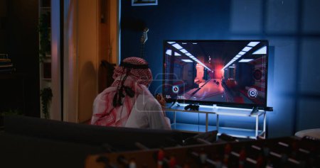 Middle Eastern gamer feeling gutted after losing singleplayer action videogame level, being outsmarted by enemies. Muslim man at home frustrated after seeing game over screen