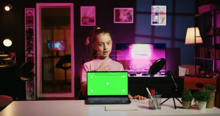 Junge Mädchen Tech Content Creator Dreharbeiten Technologie Überprüfung von Green Screen Laptop, Auspacken und Präsentation von Spezifikationen für das Publikum. Netter Gen-Z-Influencer zeigt Zuschauern Notebook-Attrappe