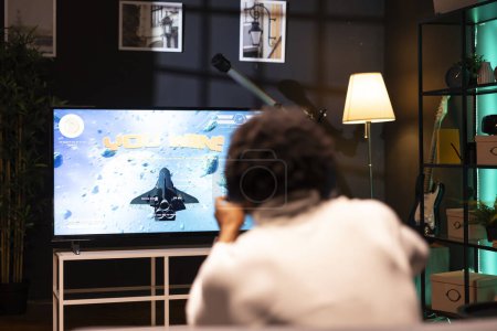 Man playing videogames on gaming console, celebrating victory after defeating all enemies. Gamer excited after winning internet esports game match on smart TV display, rejoicing