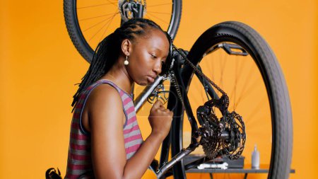 Primer plano de los pedales de empuje mecánicos para girar la rueda de la bicicleta, examinándola después de reparar y lubricar las piezas. Empleado escuchando cualquier signo de chirrido en ruidosos anillos de cadena de bicicleta, cámara B