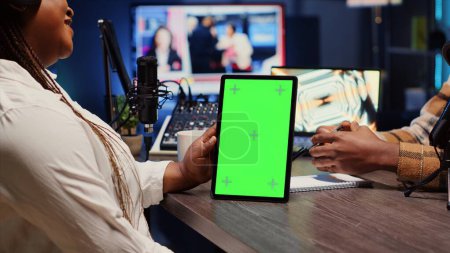 Green-Screen-Tablet, das eine Frau in einem Podcast hält und mit einem Gast während des Marathons für humanitäre Zwecke diskutiert. Chroma-Schlüsselgerät, das der Moderator benutzt, um die gesammelten Spenden des Publikums während der Show zu überprüfen