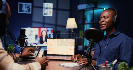 African american influencer recording podcast with man, talking in studio. Zoom in shot of cheerful man listening to guest live during broadcasting session for internet show