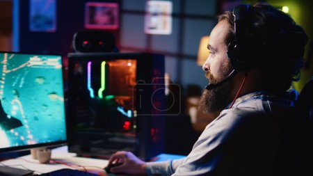 Happy man using headphones to play spaceship flying singleplayer game with overlay HUD showing health, fuel, ammo bars and minimap. Smiling gamer immersed in gaming experience, navigating universe