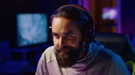 Esports player playing videogames in front of subscribers during livestream, focused on defeating enemies. Close up on cheerful pro gamer streaming game, wearing headphones
