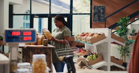 Afrikanisch-amerikanische Kunden öffnen Gläser mit Schüttgütern gefüllt, um chemiefreie Produkte und Vorräte zu kaufen. Frau auf der Suche nach umweltfreundlichen veganen Lebensmitteln, umweltfreundliches Konzept. Handschuss.