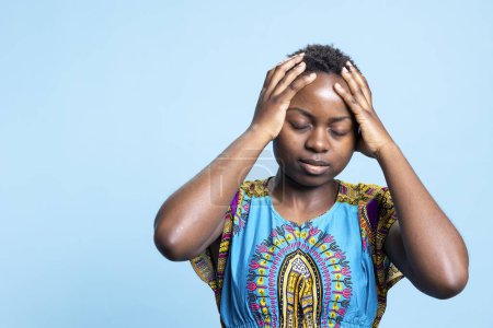 Mujer afroamericana que experimenta trastornos depresivos y síntomas de enfermedad, migraña severa en el estudio. Modelo joven con problema de salud y dolor de cabeza agonizante, se siente enfermo y sombrío.