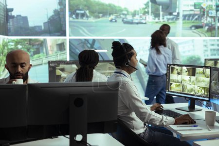 Indian operator following real time traffic footage from CCTV cameras, reporting any irregularities in the urban roads. Male employee monitoring drivers behavior and activity.